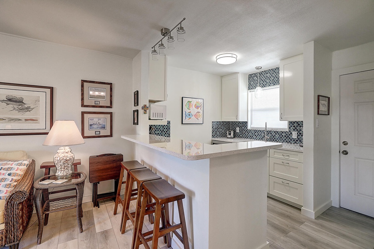 Your open kitchen features sleek white cabinets, stylish mosaic backsplash, and a breakfast bar perfect for morning coffee.