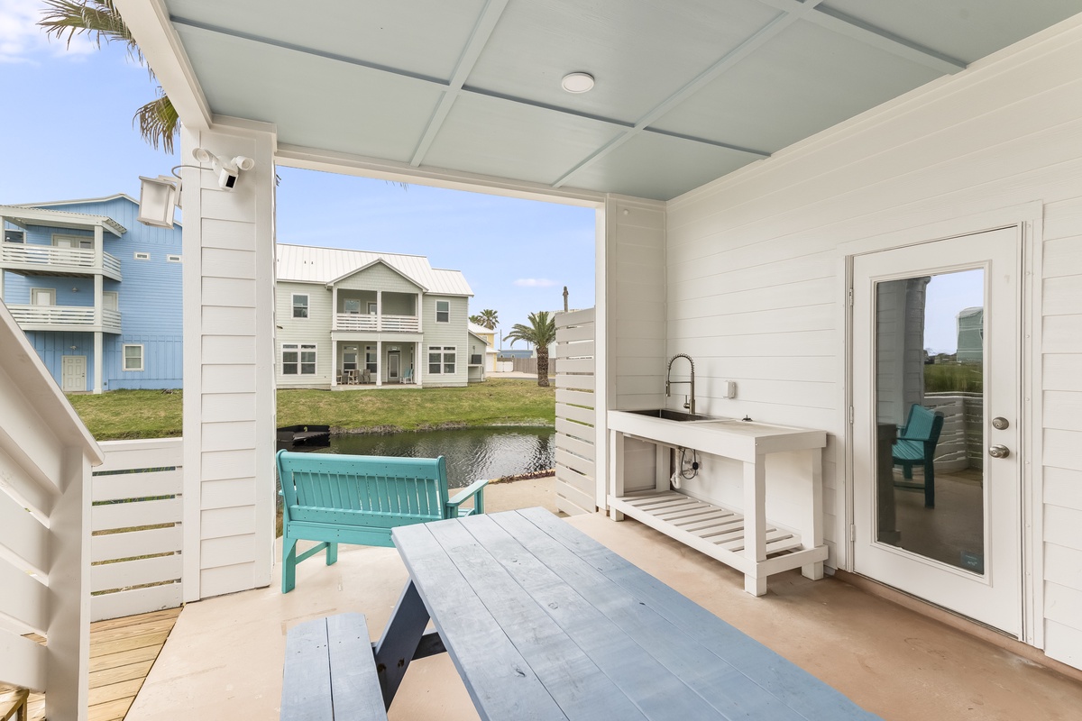 Your covered patio features a convenient cleaning station and turquoise seating overlooking the peaceful canal waters.