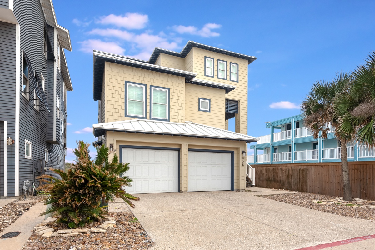 Modern beachside home with tropical landscaping and convenient two-car garage in a vibrant coastal neighborhood.