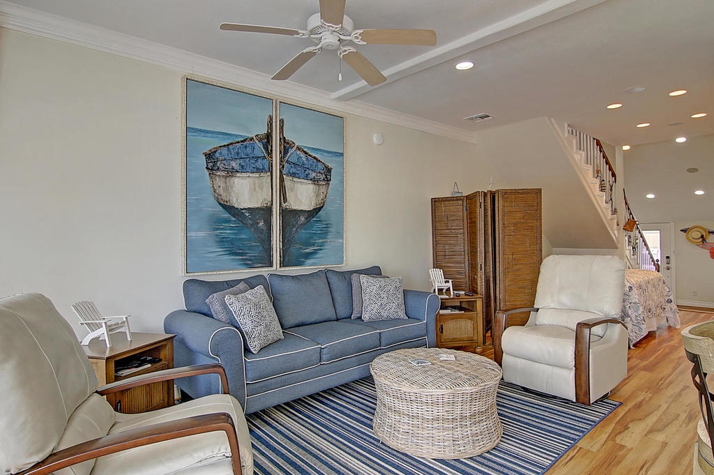 Relax in your coastal haven with nautical art, comfy seating, and warm hardwood floors beneath a gentle ceiling fan.