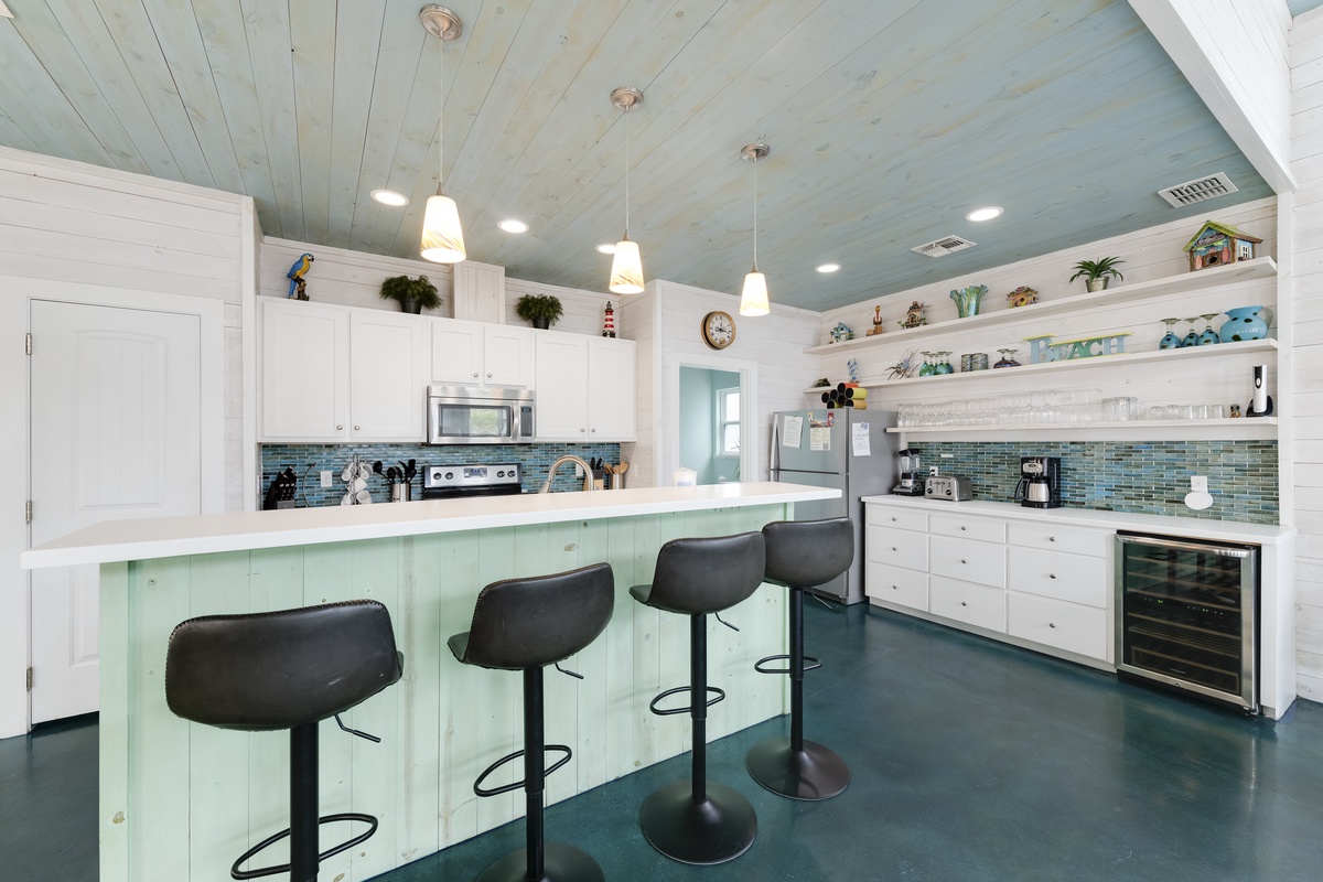 Your coastal-inspired kitchen awaits with turquoise accents, spacious island seating, and everything needed for memorable meal prep.