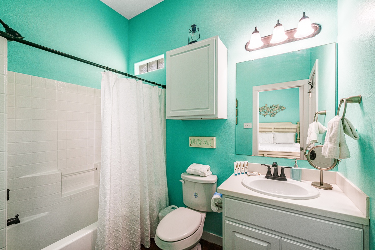 Refresh in your vibrant turquoise bathroom with a full tub-shower combo, perfect for unwinding after beach days.