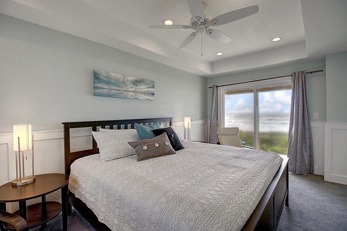 Unwind in your serene bedroom with coastal charm and peaceful views beyond the glass doors.