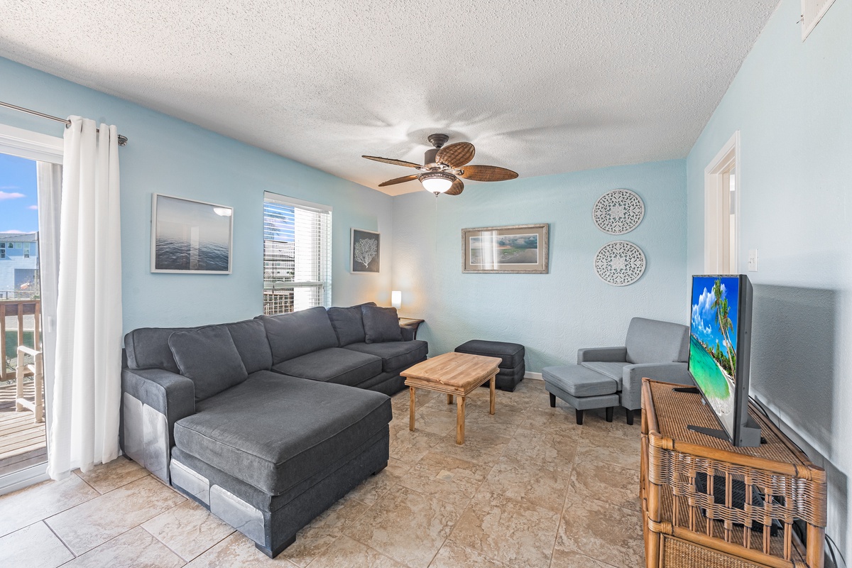 Unwind in your spacious living room with plush sectional seating, coastal decor, and ceiling fan comfort for ultimate relaxation.