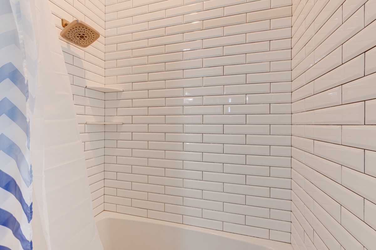 Step into your pristine tiled shower with elegant subway tile walls and gold-toned fixtures for a luxurious bathing experience.