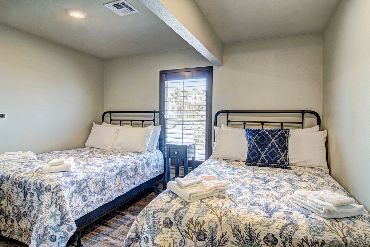 Your cozy twin bedroom features comfortable beds with fresh linens and charming coastal-themed bedding, perfect for a restful night's sleep.