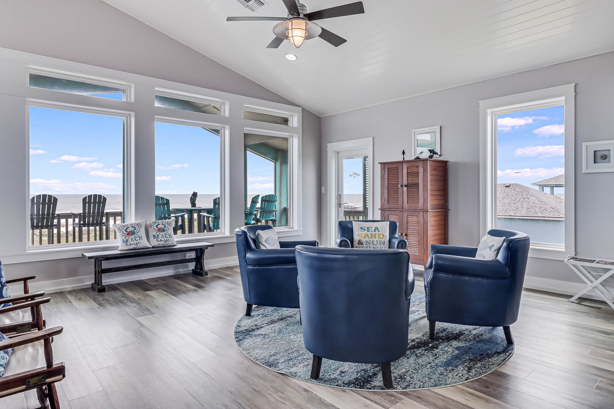 Sink into plush navy chairs while ocean breezes flow through your bright living space, where panoramic beach views create the perfect backdrop for relaxation.