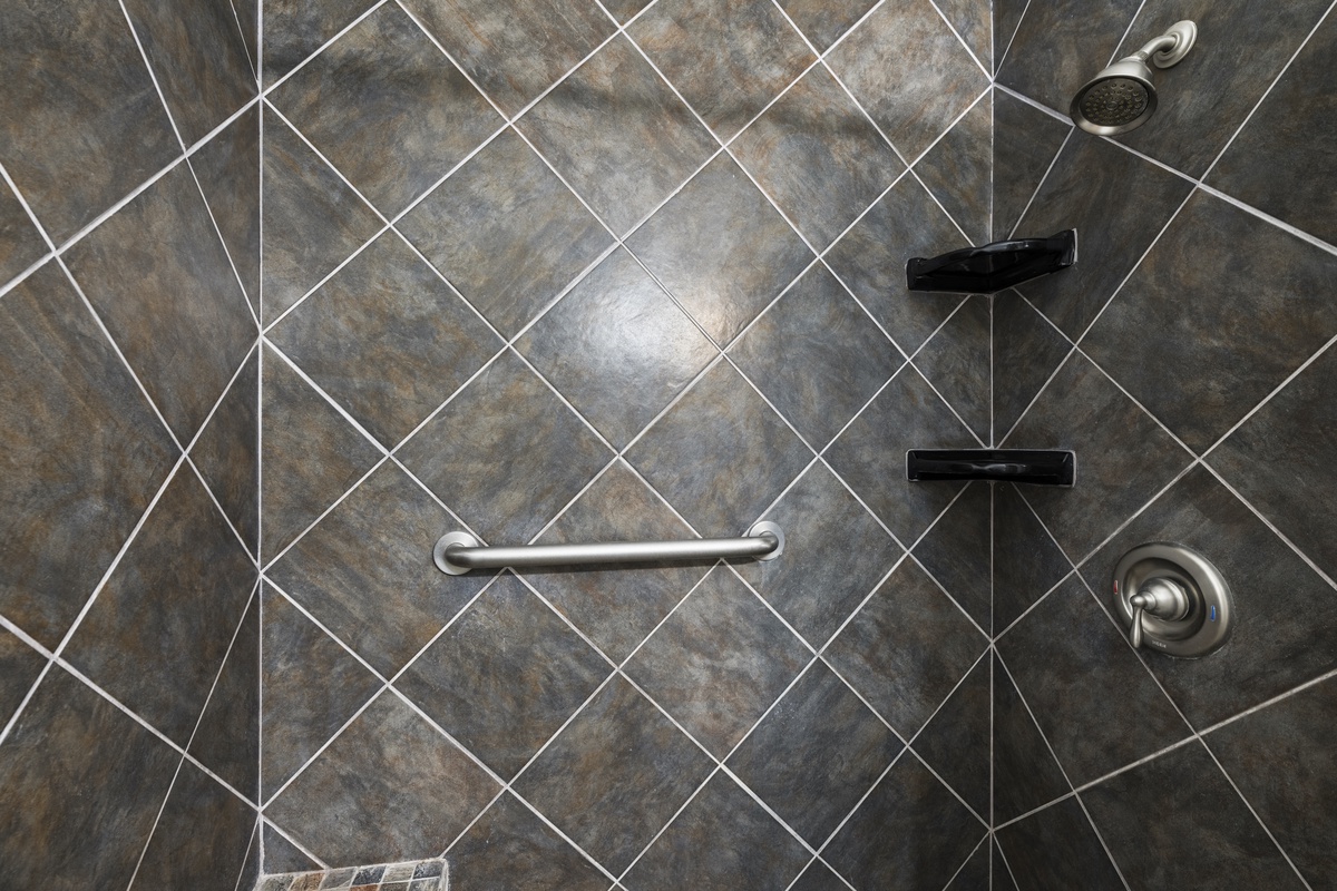 Your private shower features stylish diagonal tile, modern fixtures, and a convenient grab bar, blending comfort and accessibility for a relaxing bathing experience.