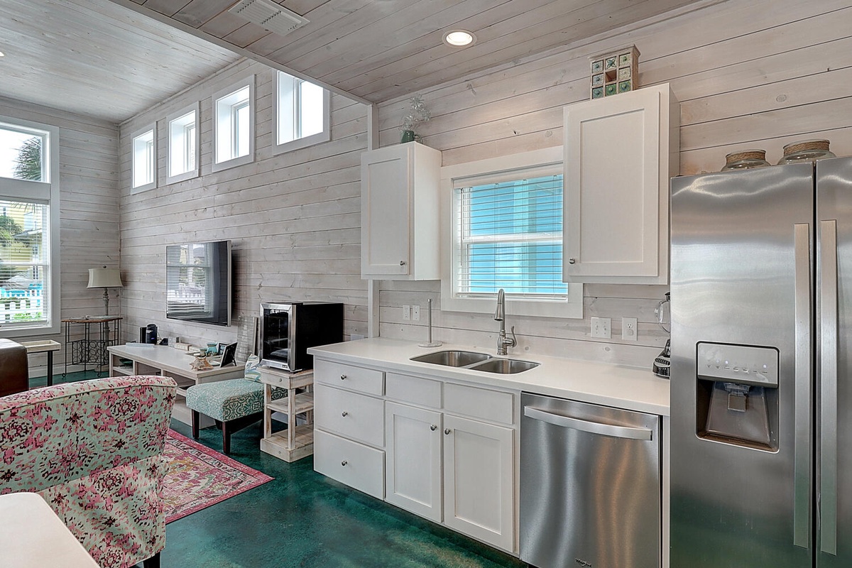 Your bright open-plan retreat blends coastal charm with modern comfort, featuring gleaming appliances and warm wood accents throughout.