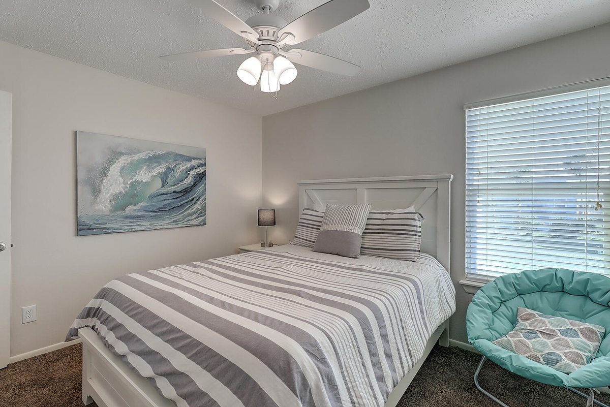 Drift off to peaceful sleep in your cozy bedroom, where coastal artwork and soft striped linens create a serene oceanside retreat.