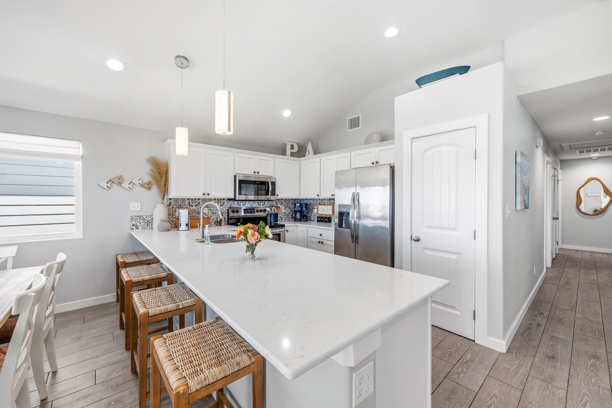 Step into your bright, modern kitchen with sleek white cabinetry, a spacious island for gathering, and stainless steel appliances—a welcoming space to cook, share meals, and create vacation memories.