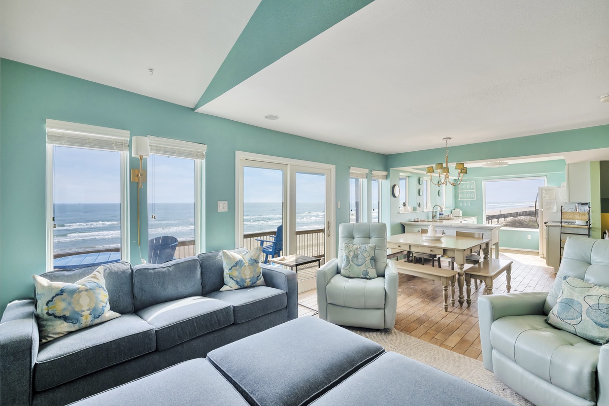 Relax in your oceanfront living space where turquoise walls meet endless sea views through floor-to-ceiling windows.