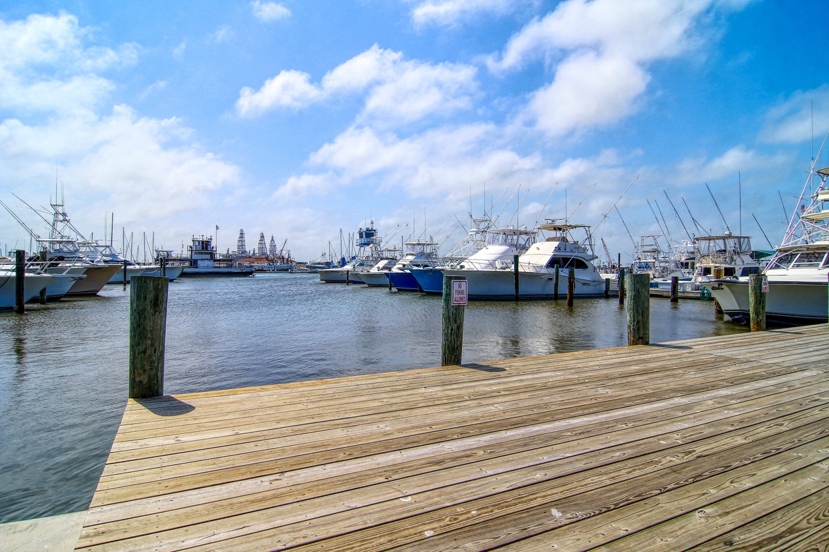 Marina boardwalk with sport fishing boats and waterfront dining nearby.