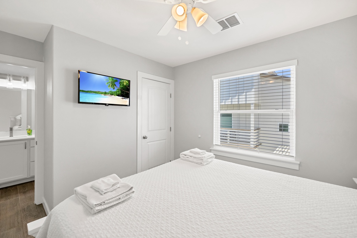 Unwind in your serene bedroom with plush linens, wall-mounted TV, and fresh towels awaiting your arrival.
