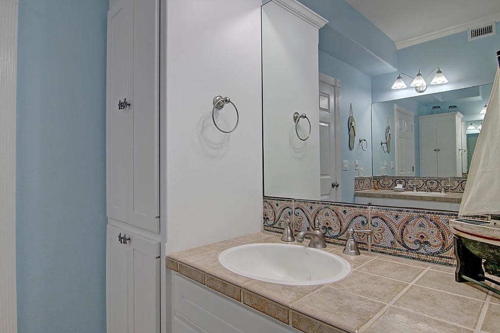 Step into your elegant bathroom sanctuary featuring soothing blue walls, beautiful mosaic tile accents, and thoughtful storage solutions for your comfort.