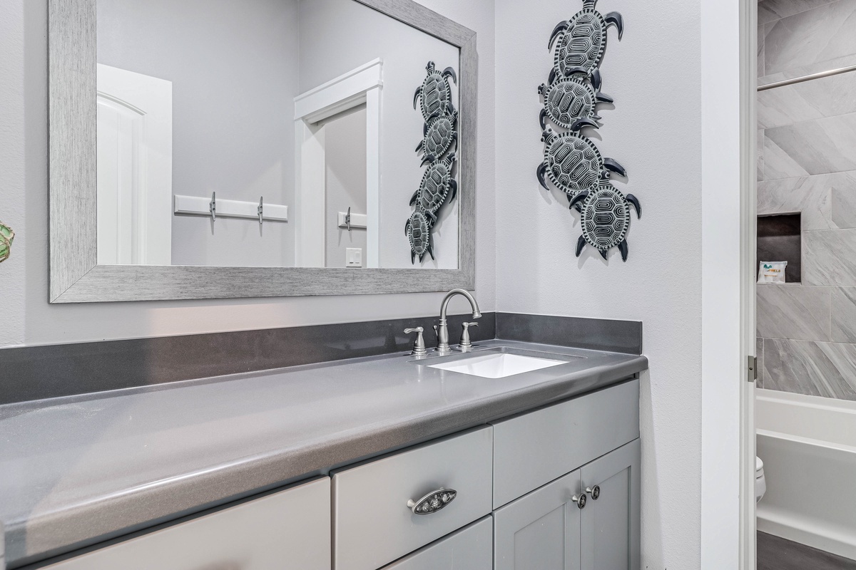 Refresh in your elegant bathroom featuring gray granite counters, coastal turtle artwork, and pristine fixtures that make daily routines feel luxurious.