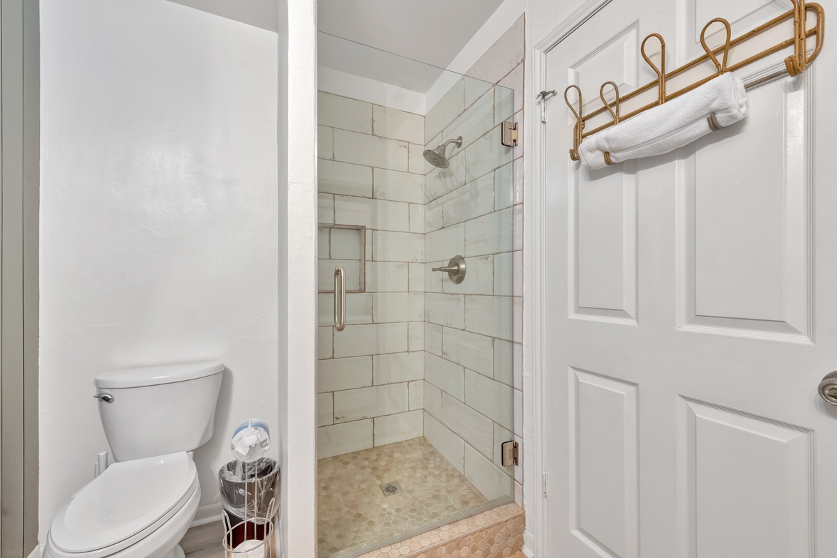 Step into your private bathroom featuring a spacious walk-in shower with elegant subway tile walls and fresh towels ready for your stay.