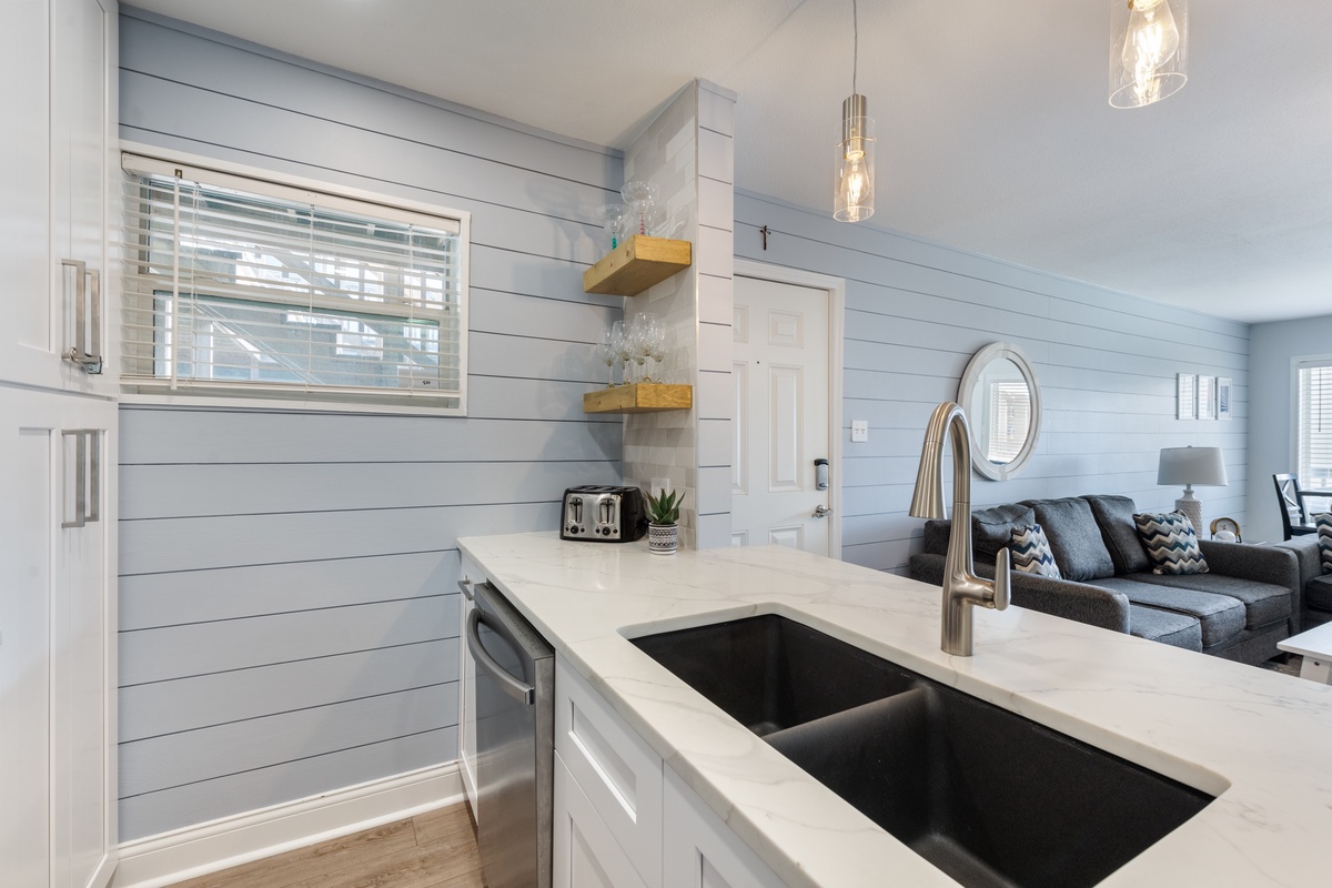 Your bright kitchen features white quartz counters, modern appliances, and pendant lighting—perfect for preparing meals while staying connected to the living area.