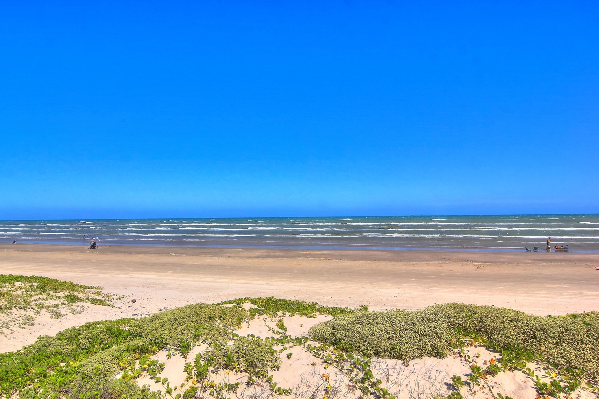 Expansive coastline with pristine sandy shores and azure waters stretching endlessly under brilliant blue skies.