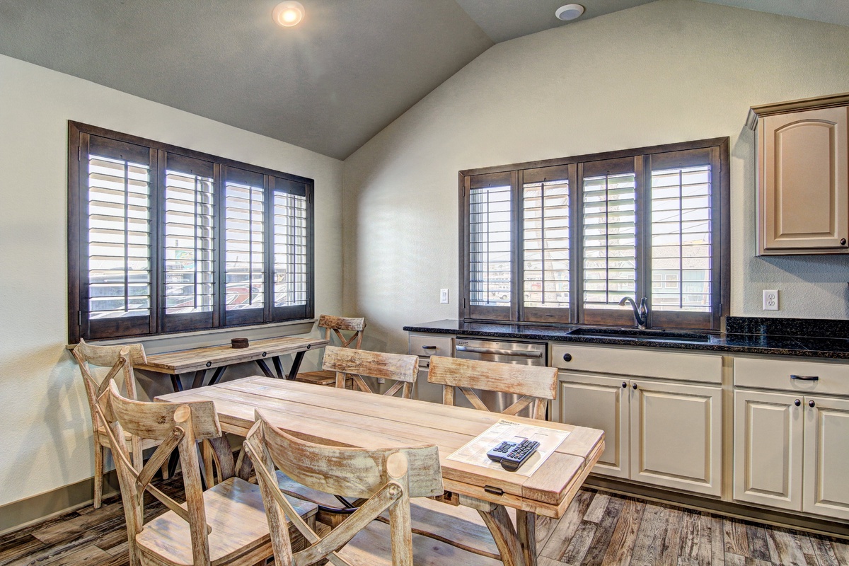 Gather around this rustic dining table where your morning coffee tastes better with natural light streaming through shuttered windows.