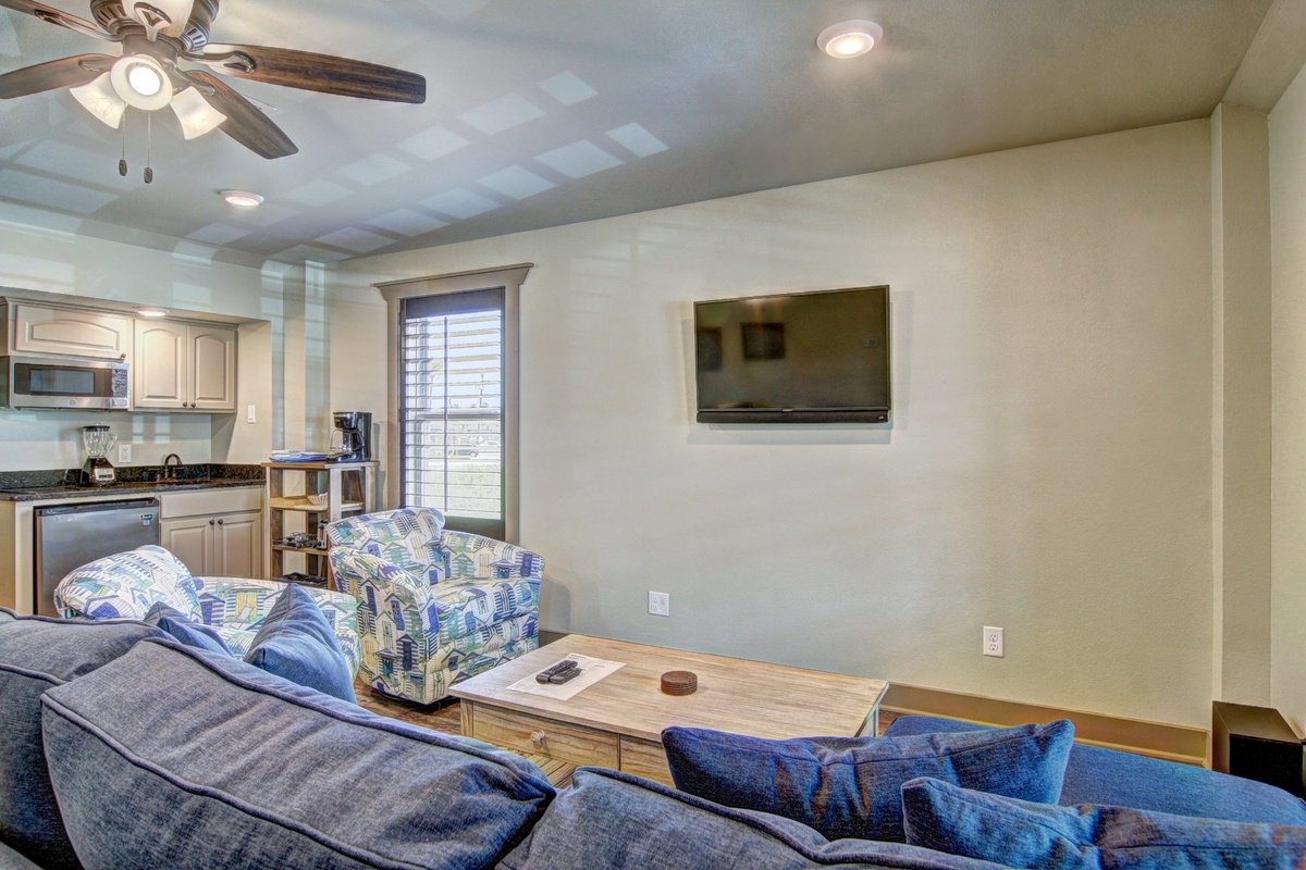 Unwind in your spacious living area featuring comfortable seating, modern kitchen access, and entertainment setup for perfect vacation relaxation.