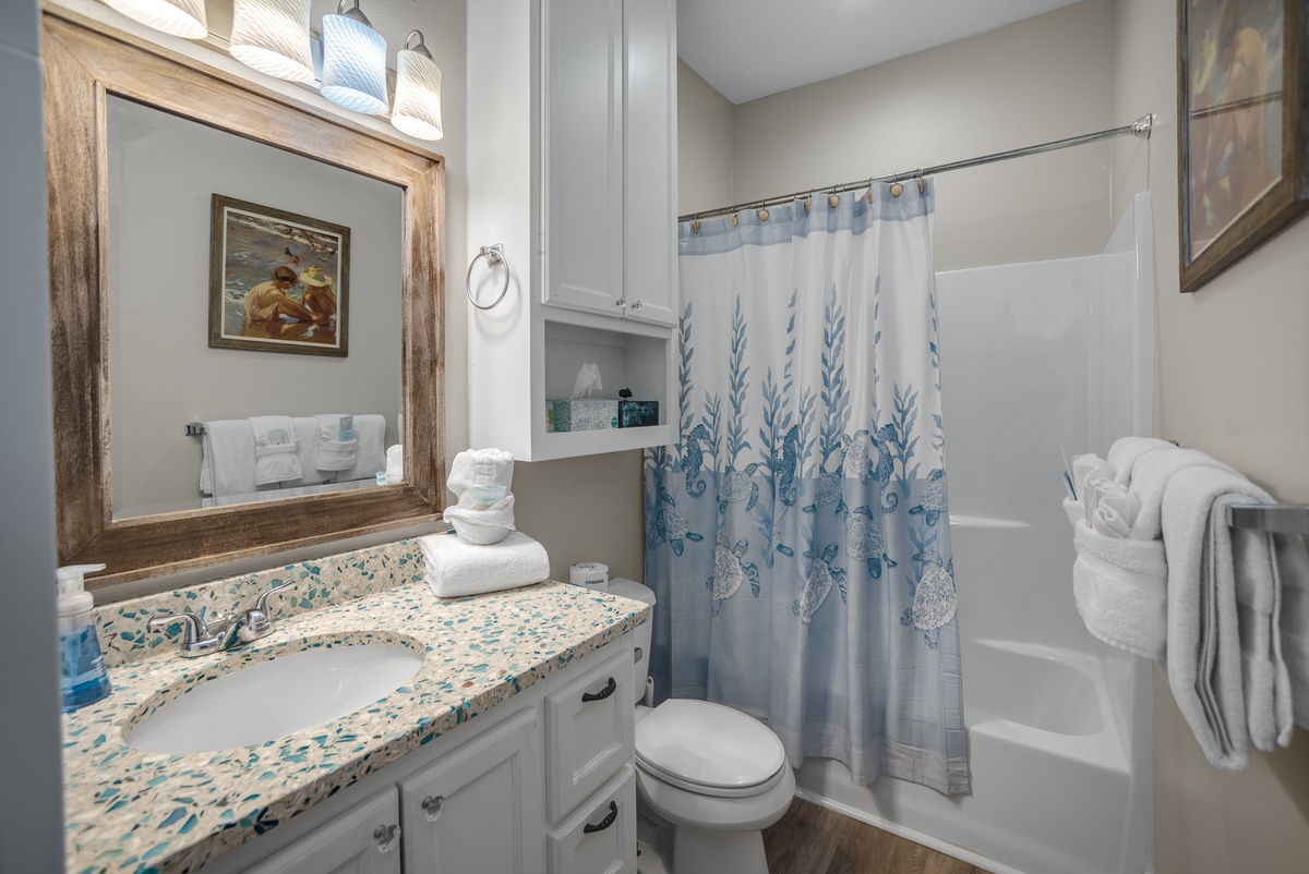 Step into your beautifully appointed bathroom featuring elegant coastal decor, soft blue accents, and plush white towels awaiting your relaxing bath or shower.
