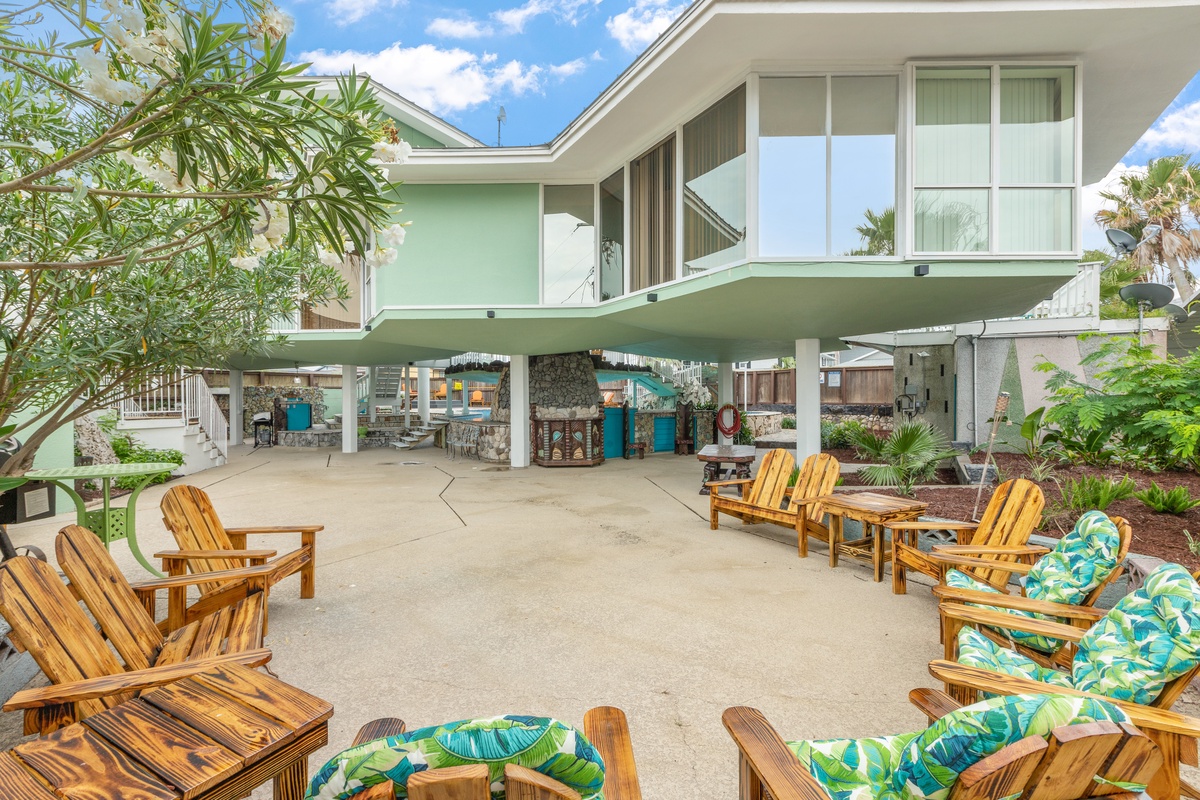 Relax in tropical-style Adirondack chairs with vibrant cushions on this expansive covered patio, perfect for unwinding after beach days.