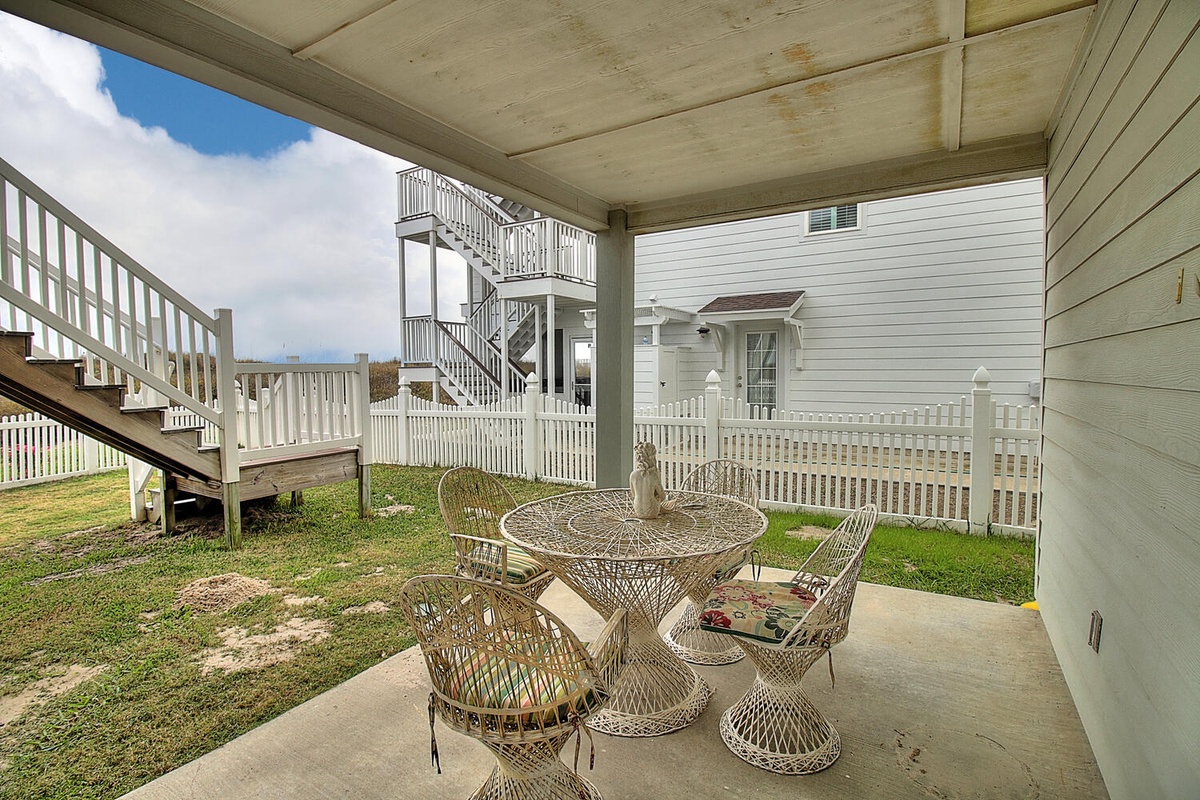 Relax on your covered patio with charming wicker seating, perfect for morning coffee or evening conversations in this peaceful coastal setting.