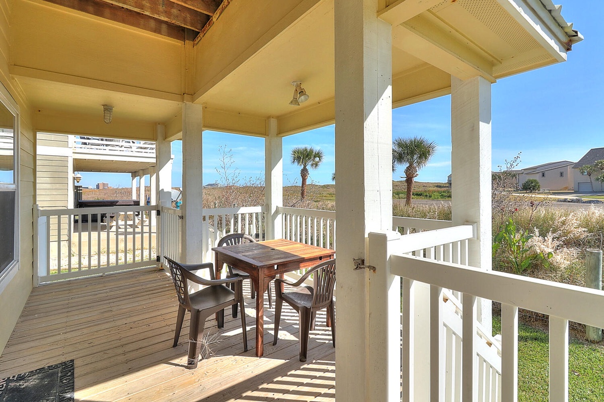 Your private covered deck offers the perfect spot for morning coffee or sunset dining, with palm trees swaying in the coastal breeze beyond.
