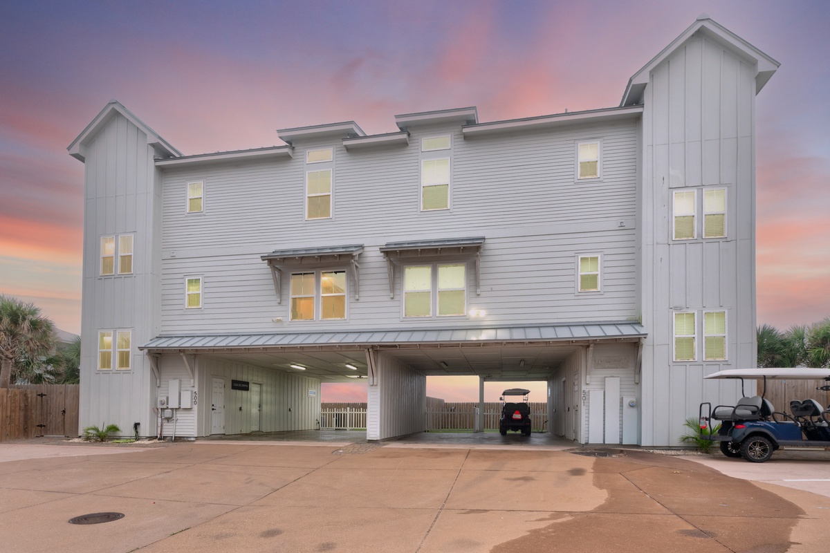 Modern coastal vacation home featuring elevated design with covered parking and stunning sunset backdrop.