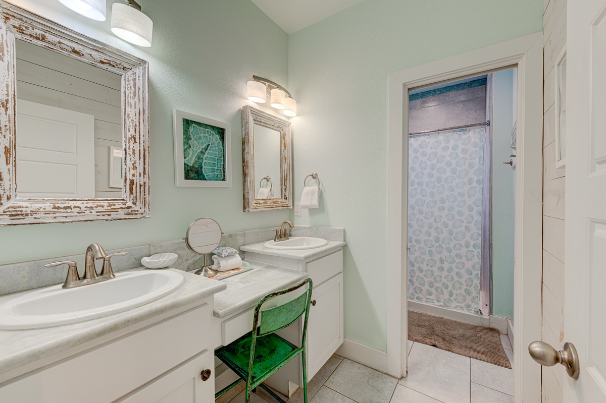 Prepare for your day in this elegant bathroom featuring dual sinks and coastal charm.