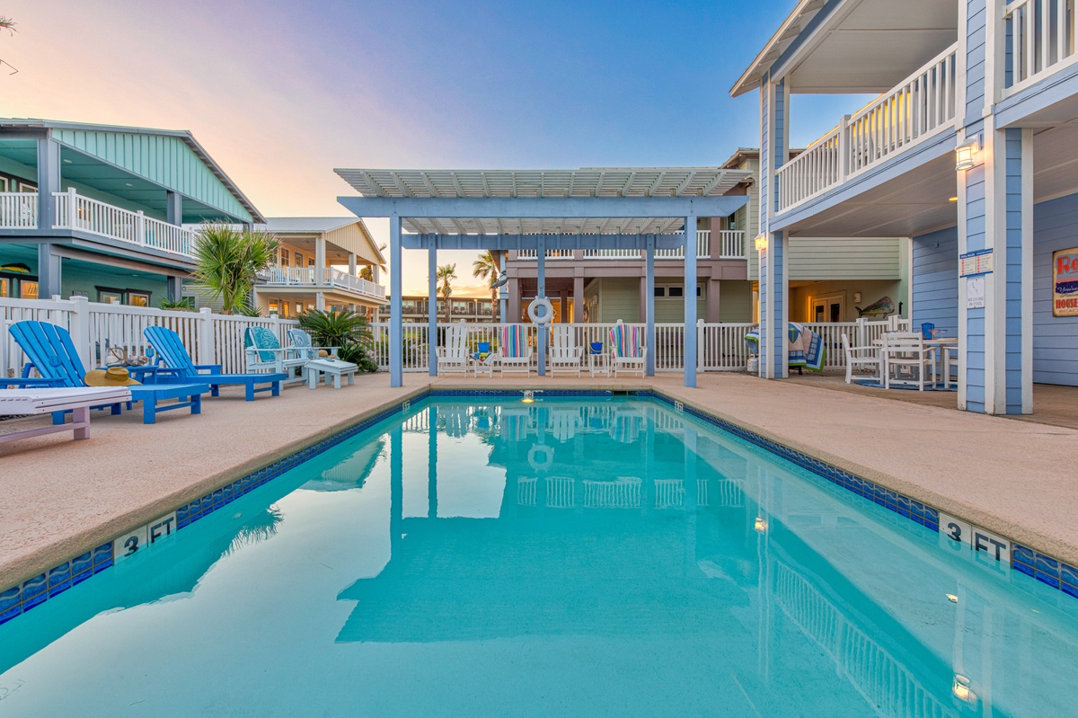 Take a refreshing dip in your private pool surrounded by colorful beach chairs and tropical palms in this stunning coastal retreat.