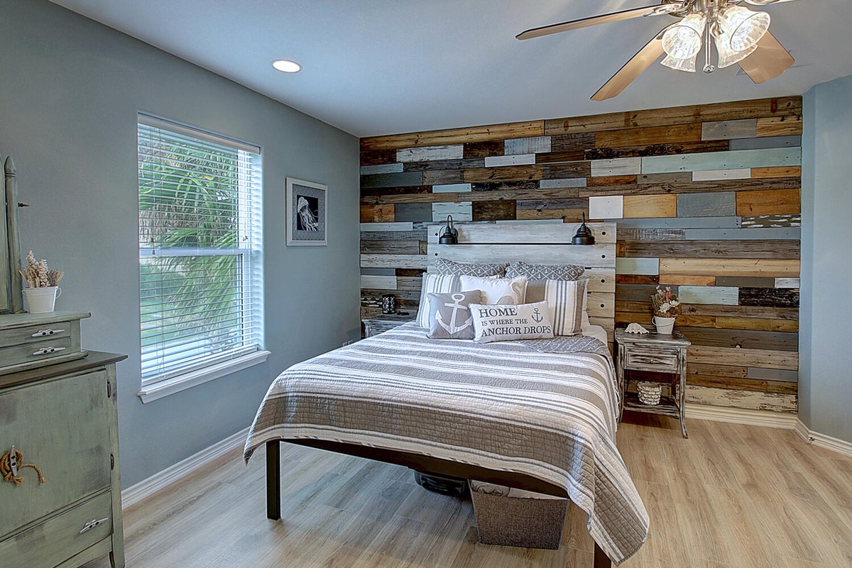 Drift off in this charming coastal bedroom where rustic wood meets nautical elegance, complete with cozy linens and gentle ceiling fan breezes.