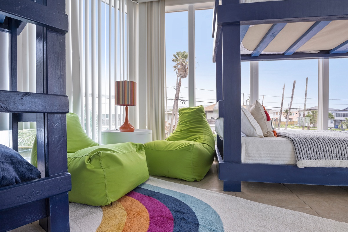 Relax in your vibrant bedroom with cozy bean bags, colorful décor, and bright windows showcasing the neighborhood views.