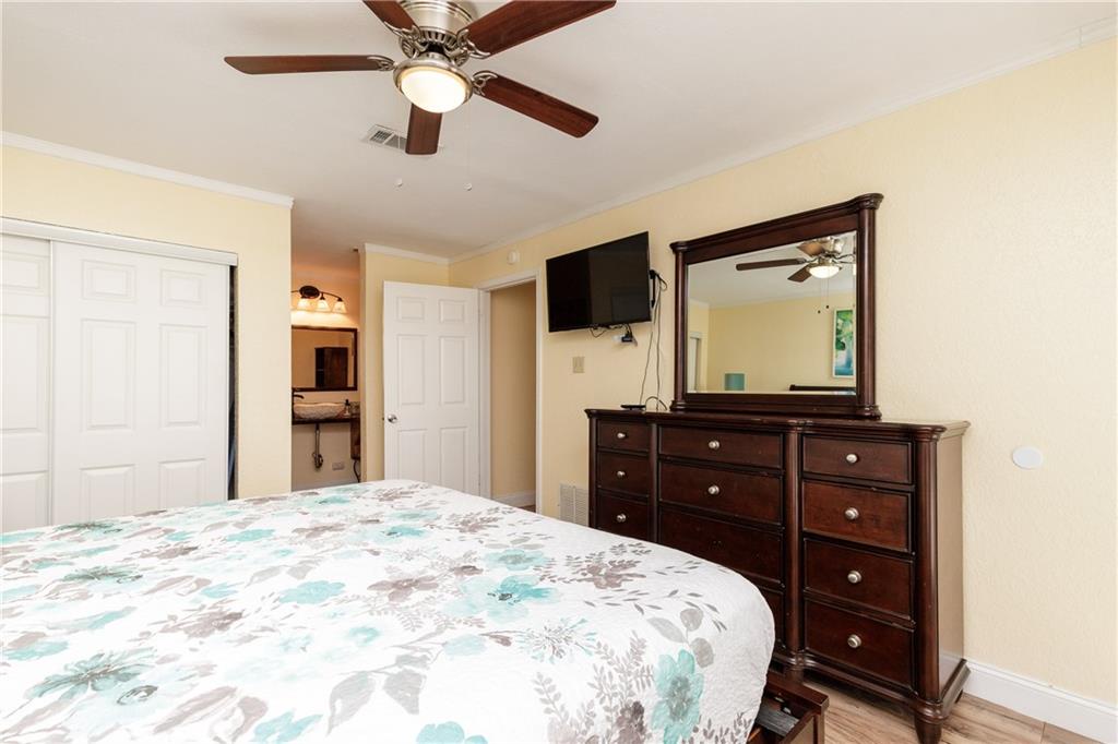 Unwind in your peaceful bedroom with elegant dark wood furnishings, ceiling fan, and wall-mounted TV for cozy evenings.
