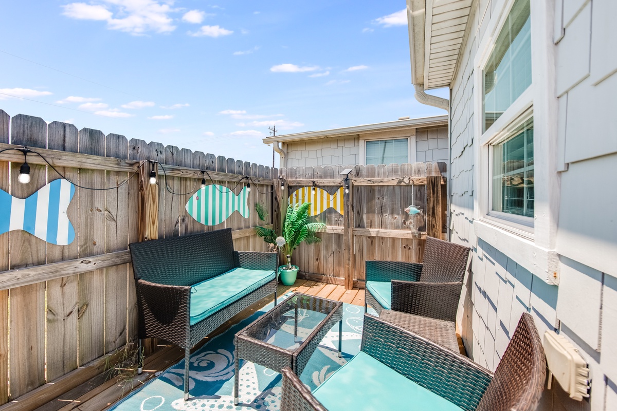 Your private patio features comfortable seating and playful beach-themed decor, perfect for morning coffee or evening relaxation under the open sky.