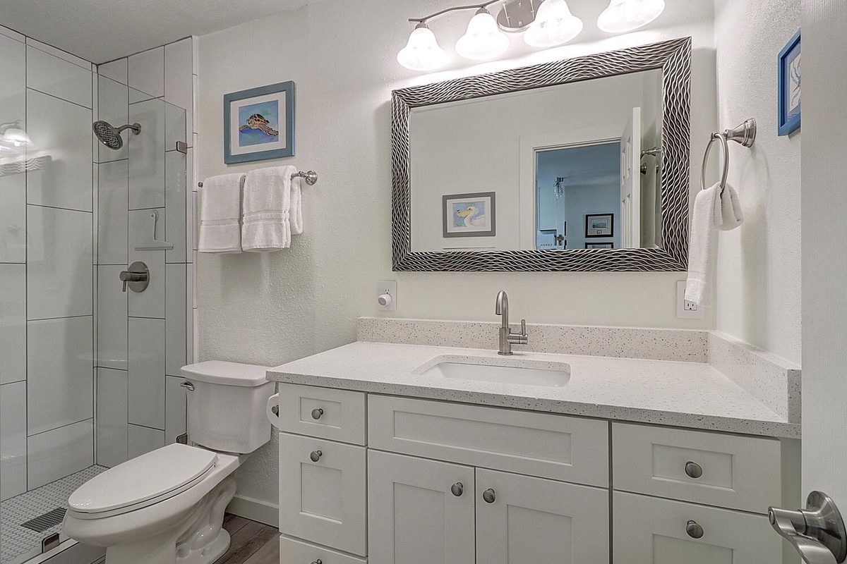Your bright bathroom features a spacious walk-in shower, elegant vanity with ample storage, and coastal artwork to create your perfect morning routine.
