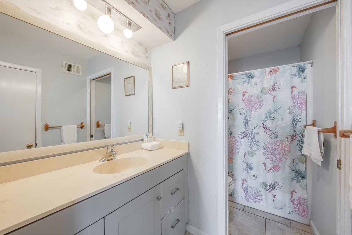 Unwind in your spacious bathroom featuring a bright vanity area and charming coral-themed shower that adds coastal flair to your daily routine.