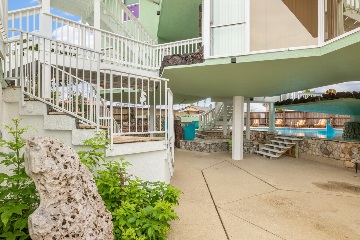 Modern multi-level property featuring white railings, stone accents, and tropical landscaping with pool access nearby.