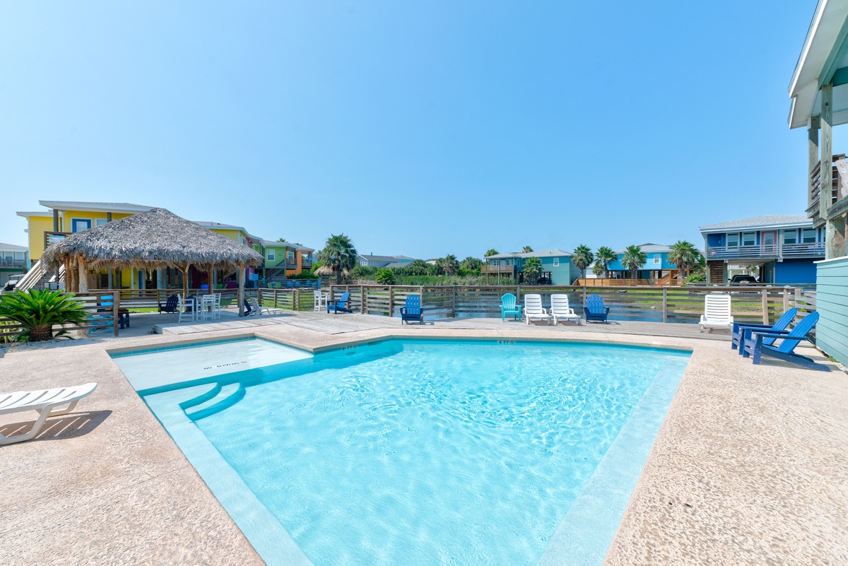 Dive into your private pool paradise surrounded by colorful beach houses and swaying palms under endless blue skies.
