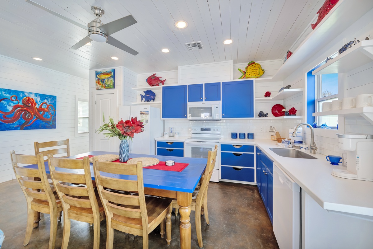 Your coastal-themed kitchen awaits with vibrant blue cabinets, full appliances, and a dining table perfect for morning coffee or family meals.