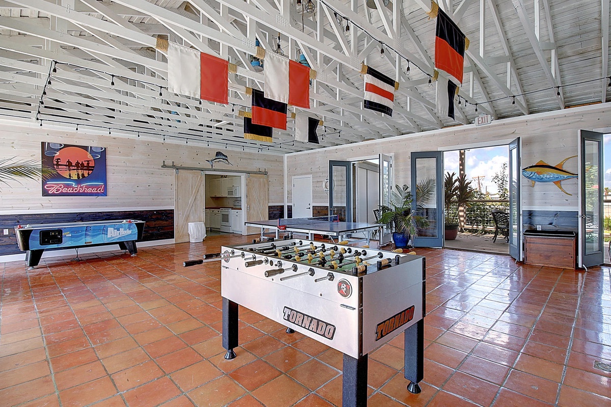Your game room awaits with foosball, air hockey, and nautical charm under soaring white beams—perfect for friendly competition and making memories.