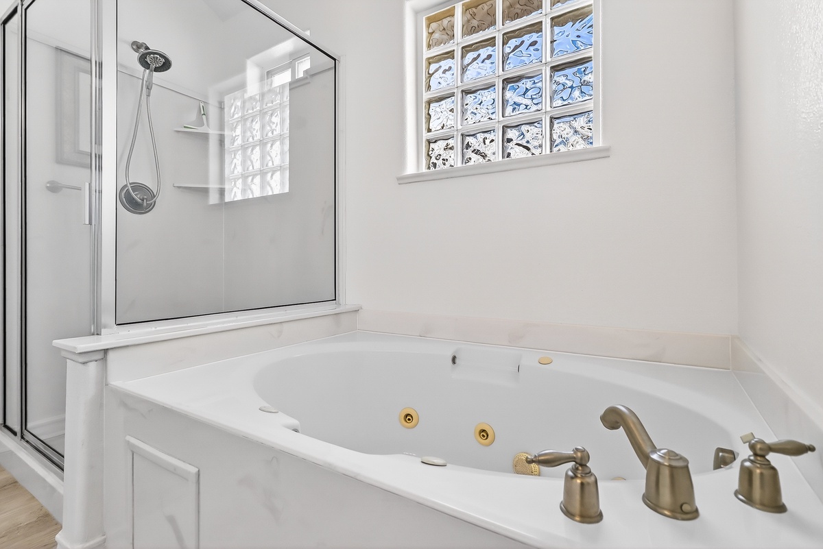 Unwind in your private spa-like bathroom featuring a luxurious jetted tub and separate glass shower for ultimate relaxation.