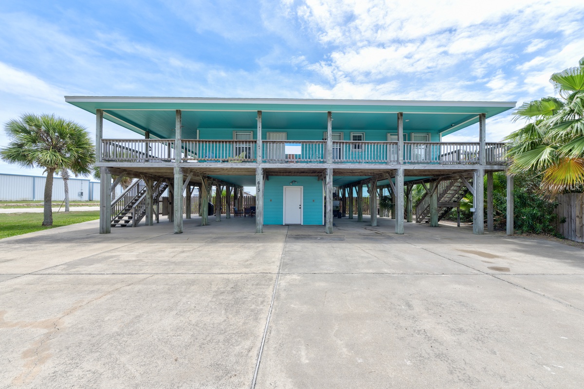 This turquoise coastal retreat is elevated on stilts, surrounded by swaying palms and offering ample parking space for easy arrival to your beach escape.