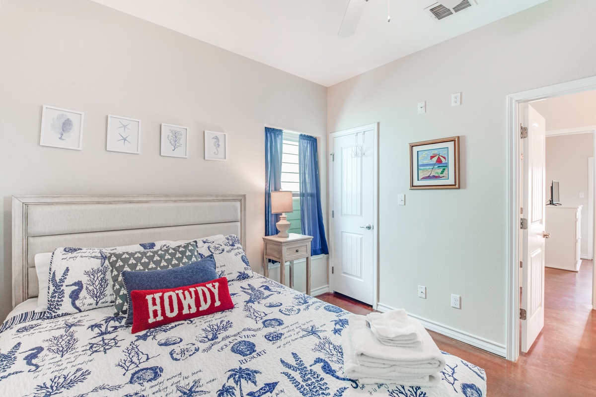 Your bright bedroom features a cozy bed with nautical-themed linens and a welcoming 'Howdy' pillow that sets the perfect tone for relaxation.