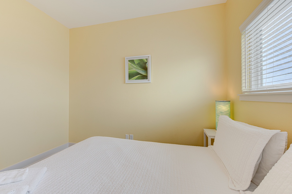 Sink into crisp white linens in your peaceful bedroom, where warm yellow walls create a sunny sanctuary for restful nights.