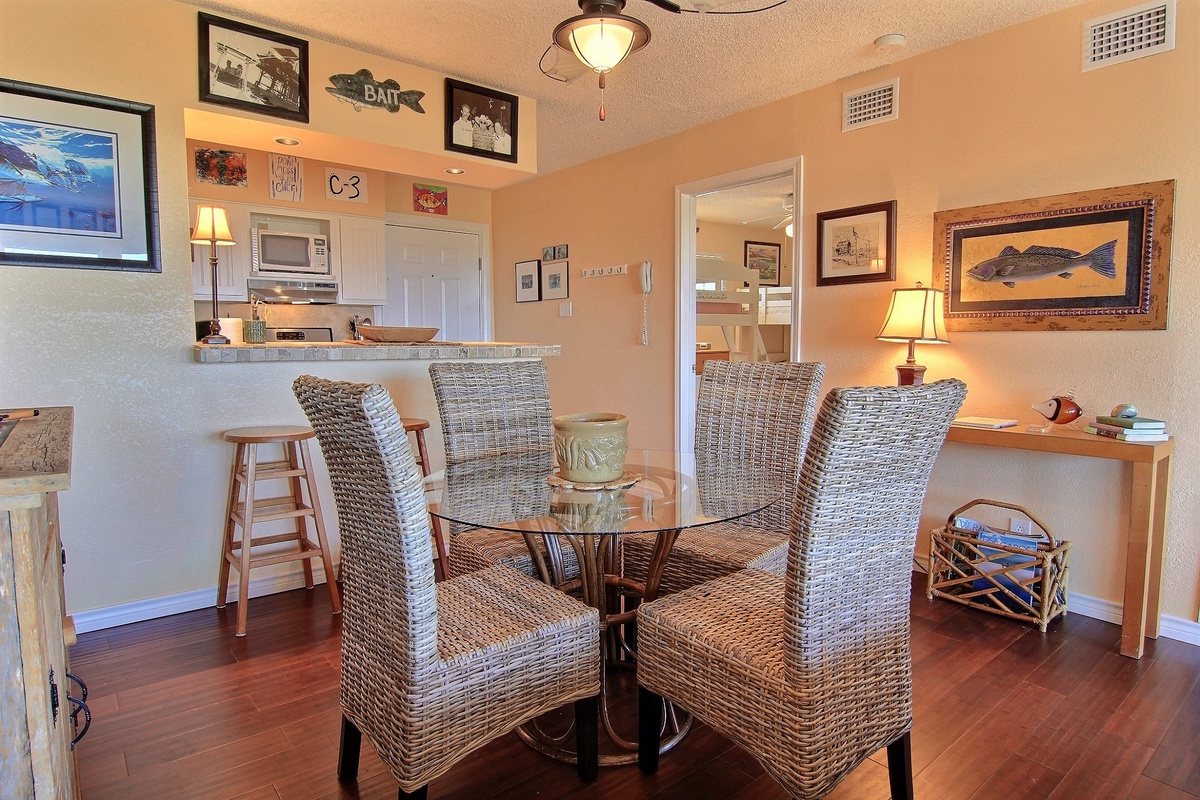 Your cozy dining area features wicker chairs around a glass table, perfect for enjoying morning coffee or evening meals with coastal charm.