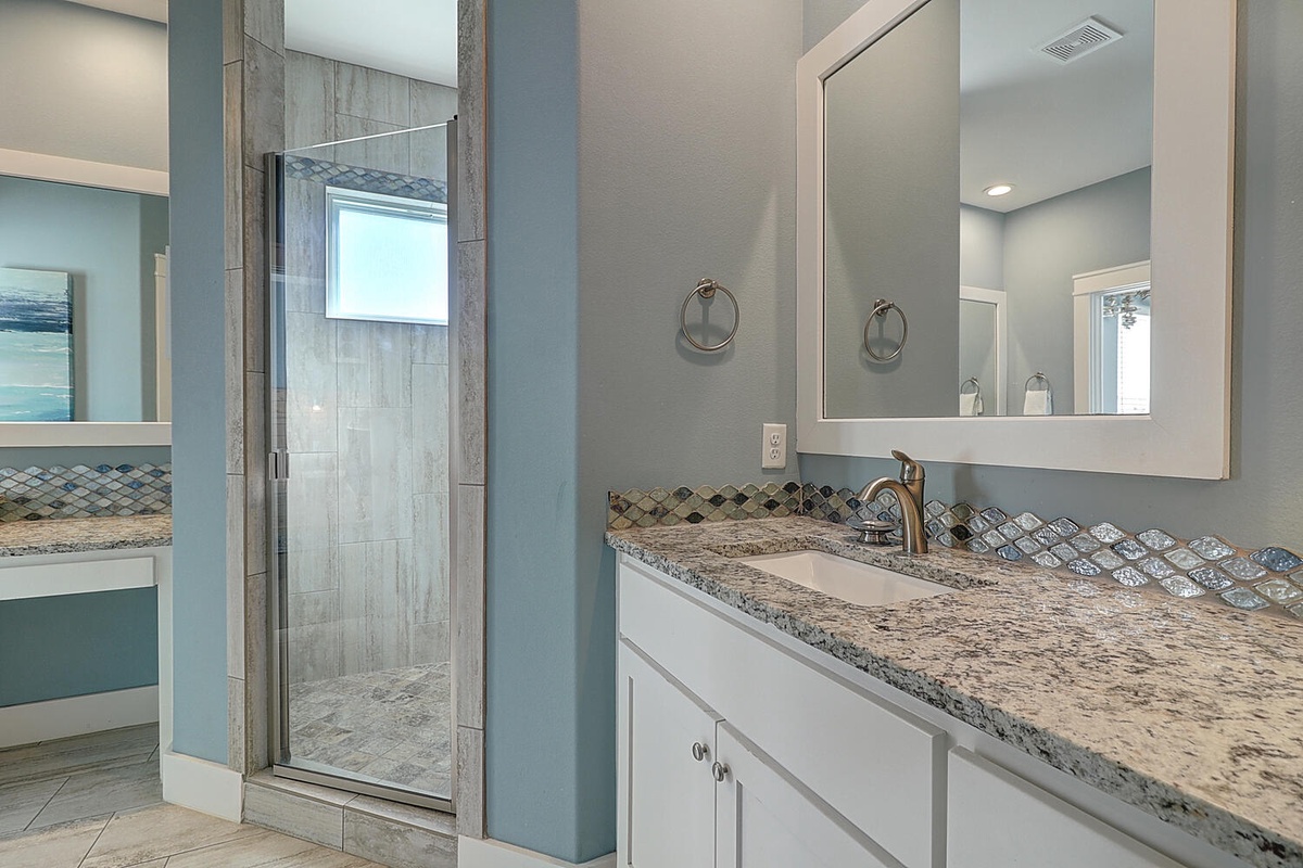 Step into your spa-like bathroom retreat with gorgeous granite counters, elegant tile work, and a spacious glass shower waiting for your relaxation.