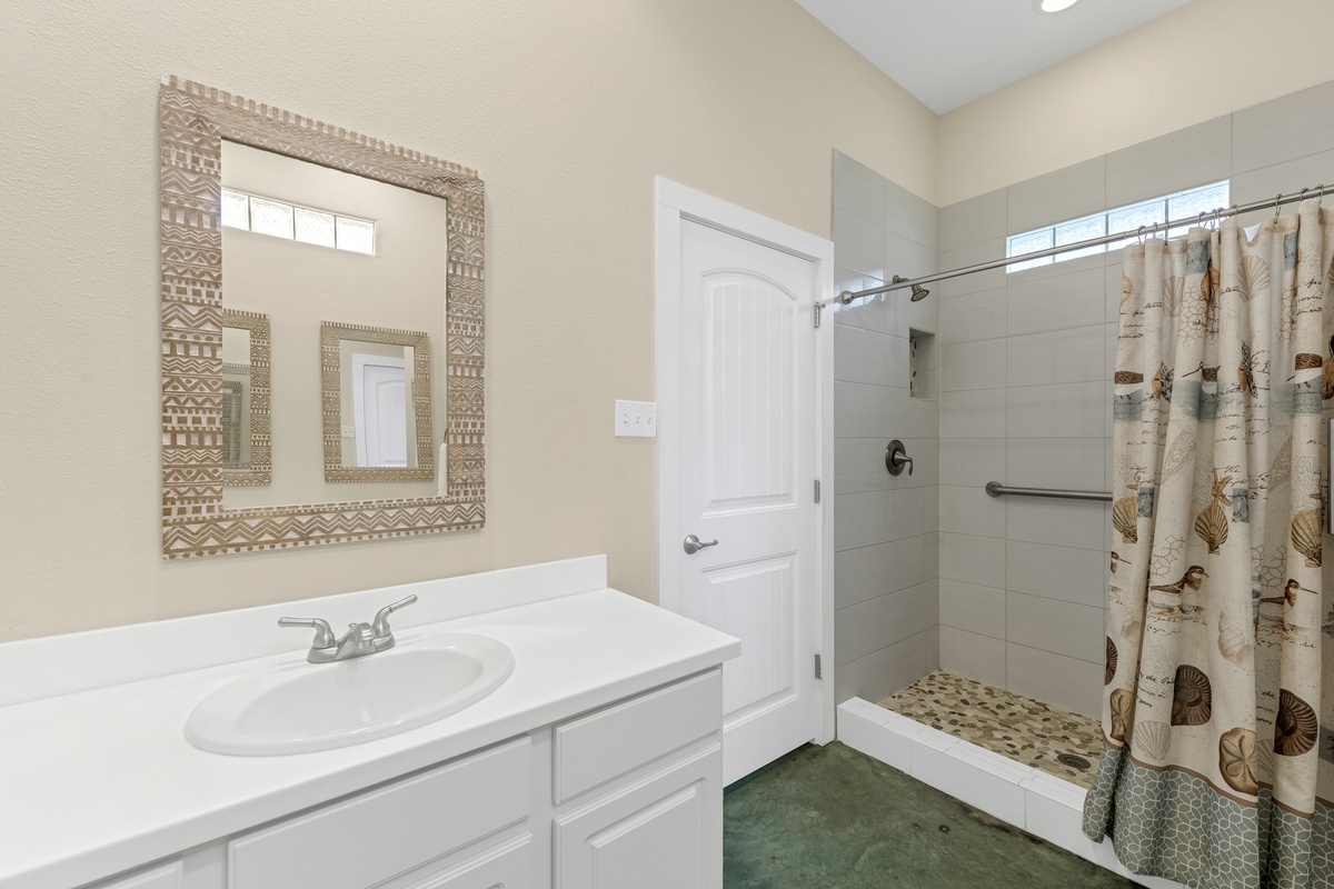Refresh in your private bathroom featuring a spacious walk-in shower and coastal-themed touches that create a serene spa-like retreat.