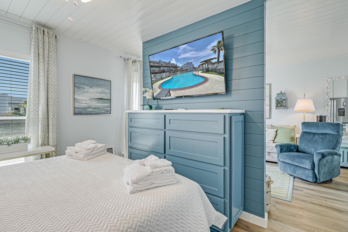 Unwind in your coastal-inspired bedroom with plush linens and a stunning blue accent wall featuring your personal TV.